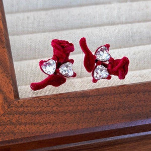 Détail de boucles d'oreilles roses en velours rouge avec zircons étincelants