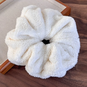 Close-up of a white fluffy scrunchie in a wooden tray with soft teddy fleece texture
