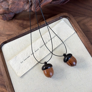 Set of two vintage sandalwood acorn pendant necklaces with black lanyards and wooden texture