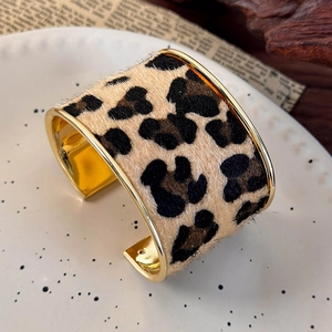 Detail of vintage wide leopard print cuff bracelet with golden metal trim and fur texture