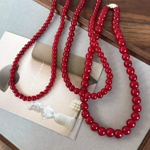 Gros plan d'un collier de perles en verre rouge avec boucle argentée sur fond artistique
