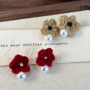 Detail of handmade knit flower earrings in red and khaki with white faux pearls