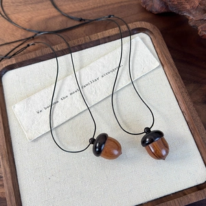 Detail of vintage sandalwood acorn pendants showing natural wood texture and carvings