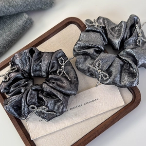 Silver glossy scrunchies set with beaded bow details and metallic fabric finish