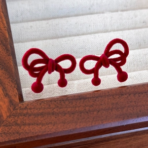 Détail de boucles d'oreilles nœud rouge avec texture velours et ornements sphériques