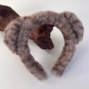 Détail du bandeau en fausse fourrure rayée marron sur un support en bois naturel