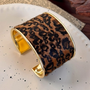 Close-up of wide leopard print open bangle with gold polished metal edges and fuzzy texture