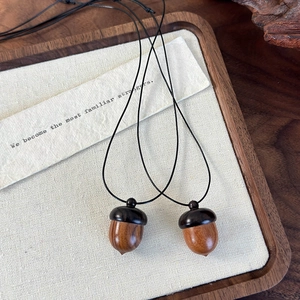 Macro detail of two vintage wood acorn pendants with natural texture on a wooden tray
