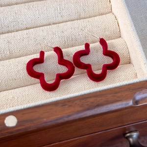 Gros plan sur des boucles d'oreilles fleurs rouges floquées dans un écrin à bijoux