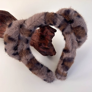 Détail d'un serre-tête oreilles de chat en peluche léopard sur support en bois naturel