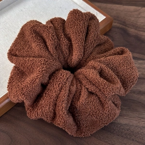 Close-up of a large dark brown plush scrunchie showing soft teddy fleece fabric texture