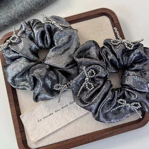 Detail of silver metallic scrunchies with beaded bow accents on a wooden tray
