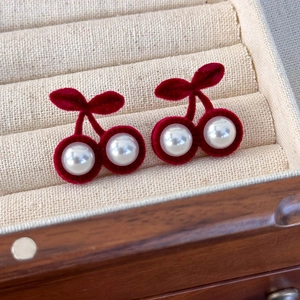 Vue macro de boucles d'oreilles cerises en velours rouge avec détails en perles blanches