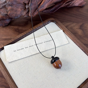 Detail of vintage sandalwood acorn pendant with natural wood grain on linen background
