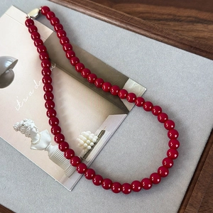 Détail du collier de perles en verre rouge avec fermoir argenté sur fond artistique