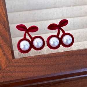 Détail des boucles d'oreilles cerise en velours rouge et perles blanches brillantes