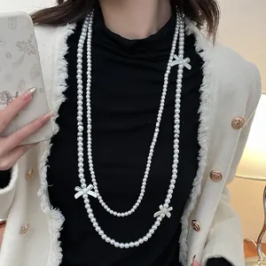 Close-up of double-layer pearl necklace with white bow accents on a black sweater