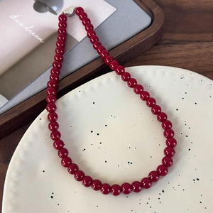 Détail d'un collier de perles en verre rouge avec boucle argentée sur assiette
