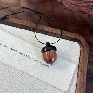 Detailed close-up of a handcrafted wooden acorn pendant with natural wood grain texture