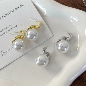Elegante Perlenohrringe in Gold und Silber mit Metallknotendesign auf einem Tablett
