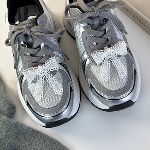 Détails de nœuds en dentelle blanche et perles sur lacets de baskets argentées