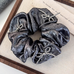 Detail of grey scrunchie with metallic glitter fabric and beaded silver bow ornaments