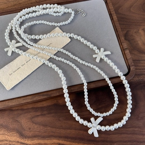 Close-up of double-layer pearl necklace with bow accents on grey velvet display