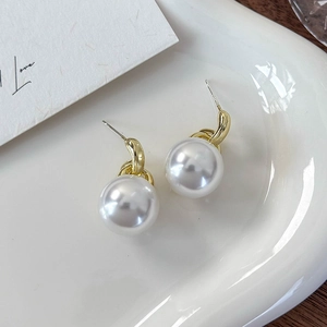 Nahaufnahme weißer Perlenohrringe auf einer weißen Keramikschale mit Goldhaken