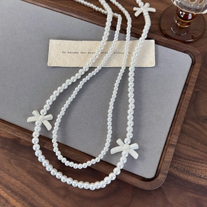 Elegant layered pearl necklace with white bow accents in a vintage aesthetic style