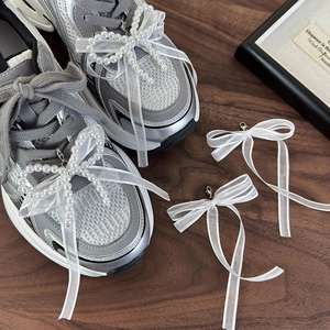 Dettaglio del ciondolo per scarpe in pizzo bianco con perle e chiusura a moschettone su scarpe