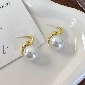 Detailaufnahme eleganter Gold-Perlenohrringe auf einem weißen Keramiktablett