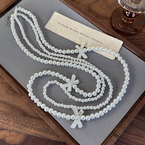 Detail of double-layer pearl necklace with silver bow accents on a velvet jewelry tray