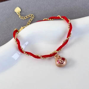 Detailed close-up of handmade red braided bracelet with gold beads and Ji character charm