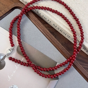 Vue détaillée des perles rouge foncé et du fermoir en argent de ce long collier élégant