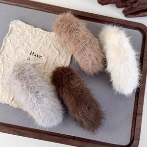 Soft plush banana hair clips in neutral colors presented on a vintage style tray