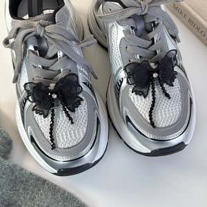 Gros plan de boucles de chaussures en dentelle noire avec strass et glands sur baskets