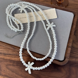 Detail of double-layer pearl necklace featuring three matte white bows and silver extender chain