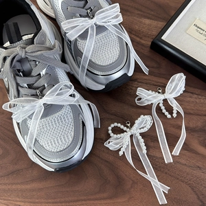 Dettaglio di ciondolo per scarpe in pizzo con perle e chiusura a moschettone in metallo