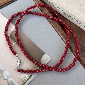 Macro d'un collier minimaliste de perles rouge foncé avec un fermoir mousqueton argenté