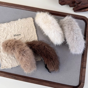 Set of soft plush banana hair clips in neutral colors on a wooden tray for winter styling