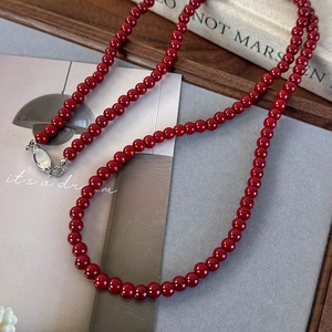 Gros plan détaillé des perles rouge foncé et de la boucle en argent sur un collier chic
