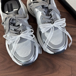 Dettaglio di grandi fiocchi di pizzo organza bianchi su sneakers in mesh argento