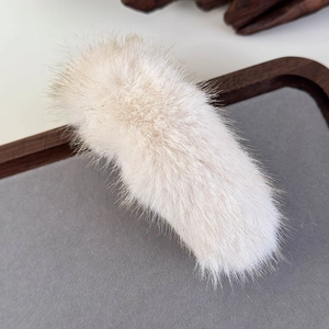 Detailed close-up of soft fluffy cream faux mink hair clip on a premium display tray