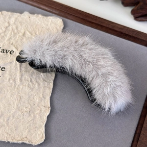 Detail showing the gray faux fur texture and black plastic base of the banana hair clip