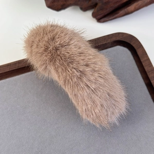 Close-up of soft fluffy light brown plush banana hair clip on a display tray