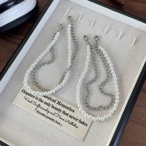 Detail of double-layer shoe charm chain with faux pearls and silver metal links on a tray