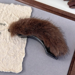 Close-up of soft brown faux fur banana hair clip with glossy base for autumn styling