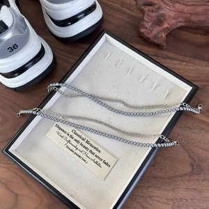 Detail of double-layer shoe accessory with blue imitation pearls and silver metal chain