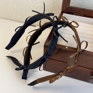 Elegant satin bow headbands in black and bronze displayed on a vintage jewelry box