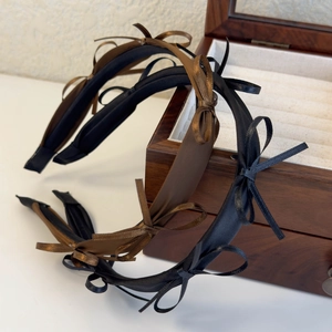 French style satin bow headbands in black and brown on a wooden jewelry box display